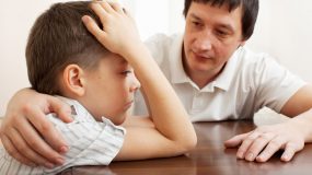 father comforts a sad bullied child.
