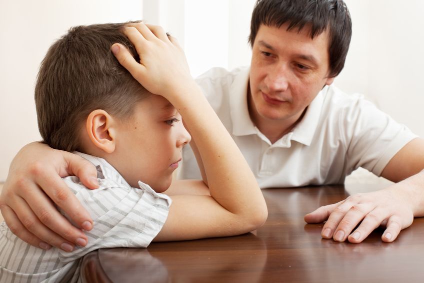 father comforts a sad bullied child. 